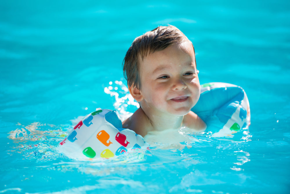 Child with floaties swimming in a clean pool.