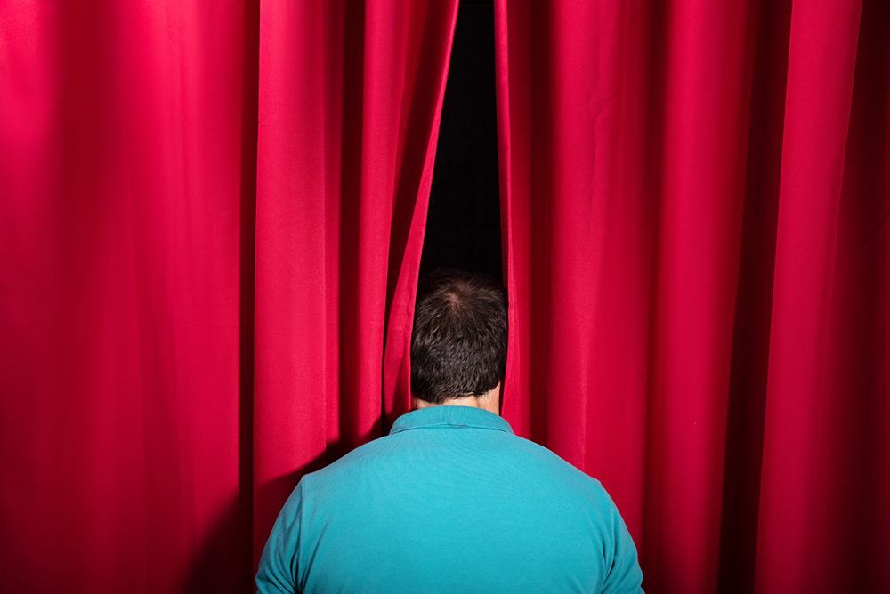 man peaking behind the curtain